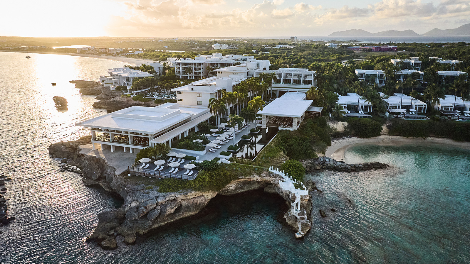 Four Seasons Resort and Residences Anguilla – Luftaufnahme des Resorts an der Küste bei Sonnenuntergang