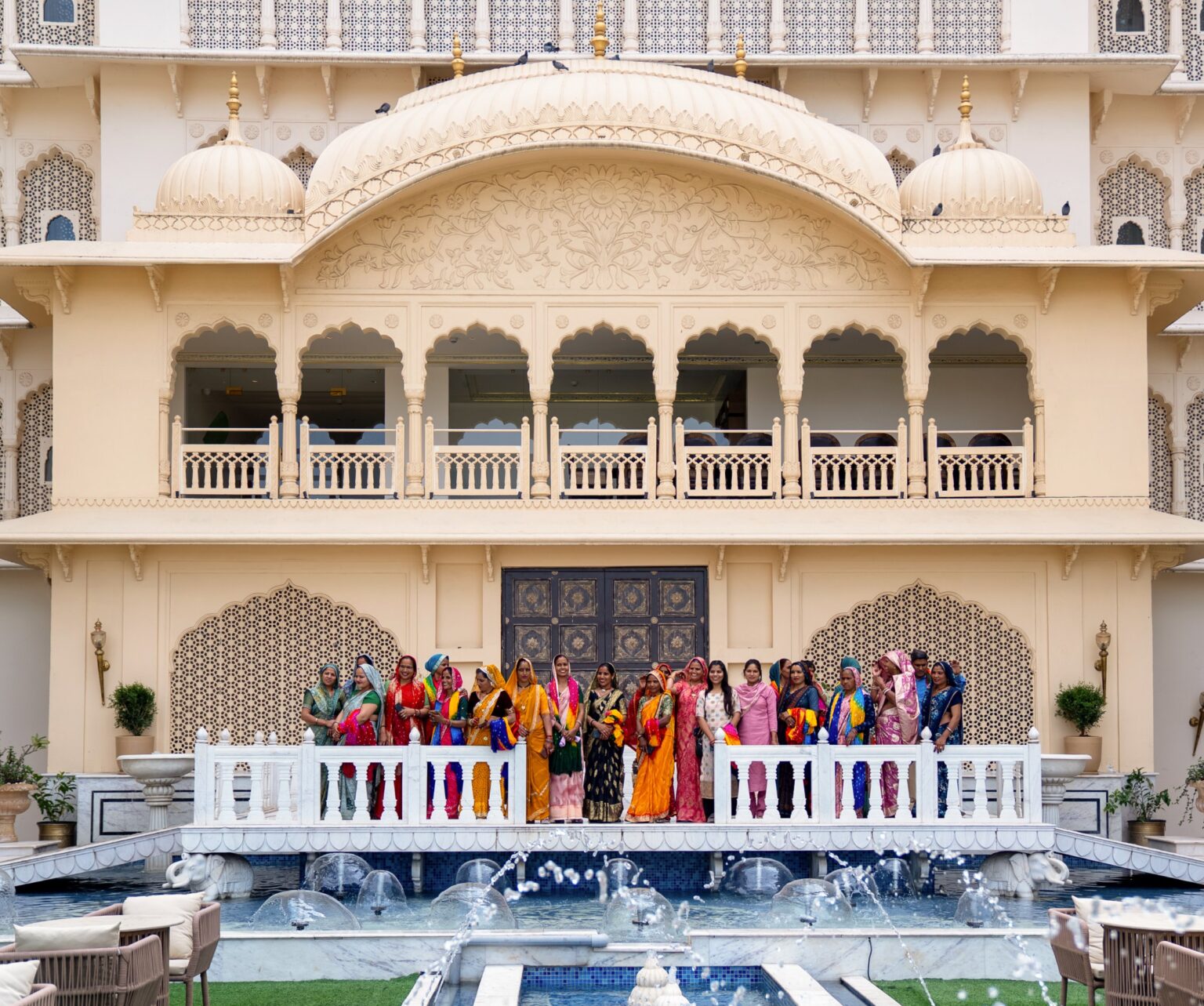 Arkaden und Kuppeln, davor Weberinnen der Jaipur Rugs Foundation