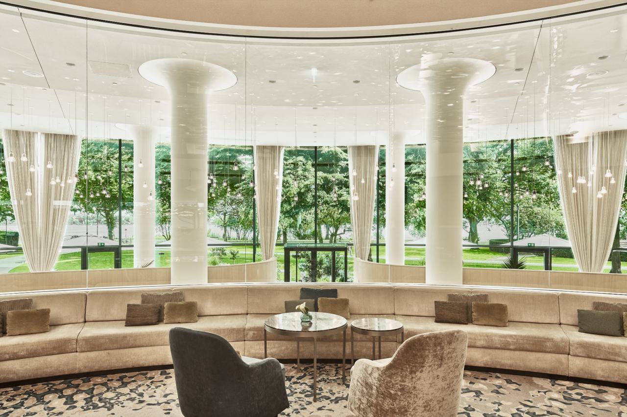 Atrium Lounge mit Säulen, Rundsofa und Blick in den Park