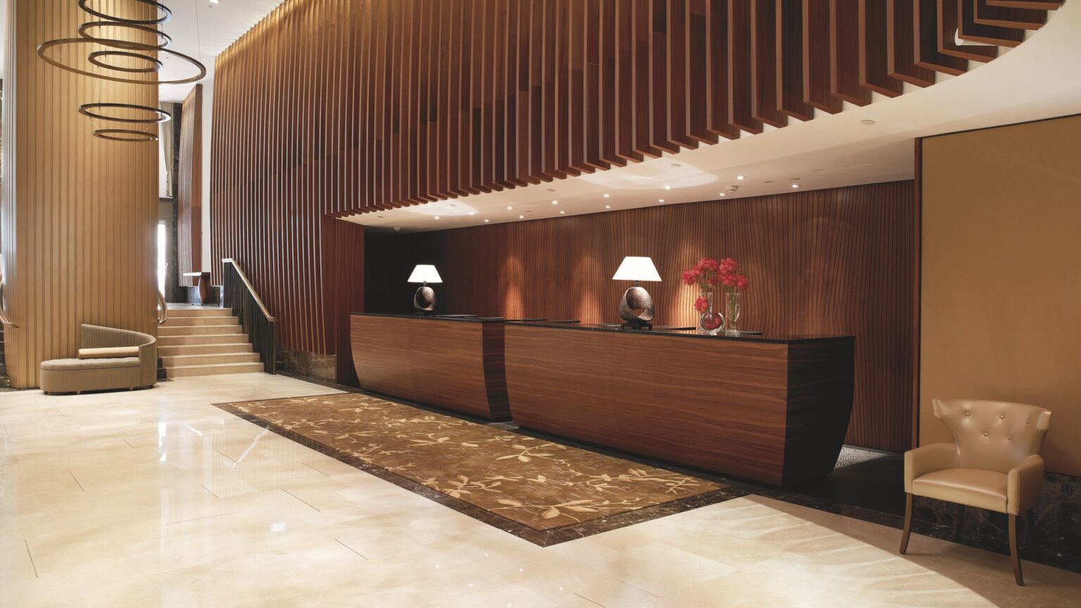 Lobby mit Rezeption, Holzlamellen und hellem Stein