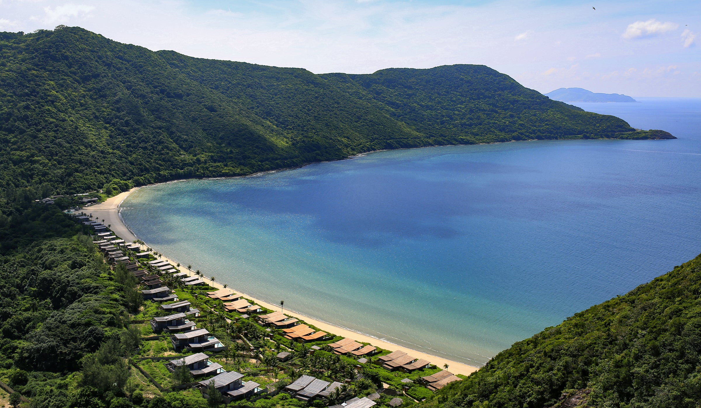 Six Senses Con Dao – Luftaufnahme der Bucht mit Villen am Strand vor grünen Bergen