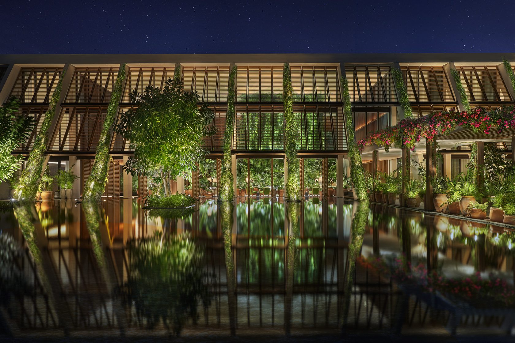 The Riviera Maya EDITION At Kanai – Begrünte Hotelfassade spiegelt sich nachts im Wasserbecken